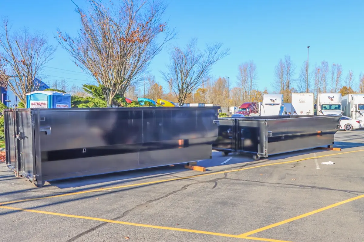 Professional dumpster rental service with roll-off container on residential driveway in Pella